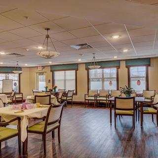 Spacious dining area with neatly arranged tables and chairs, featuring large windows and warm lighting.