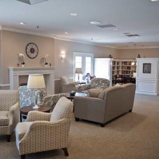 A cozy living room with comfortable seating arrangements, lamps, and a bookshelf.