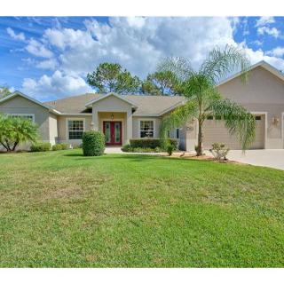 A suburban house with a well-maintained front lawn and palm trees under a partly cloudy sky.