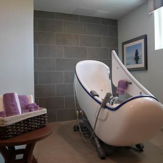 A modern bathroom featuring a unique spa bathtub with lavender towels and minimalist decor.