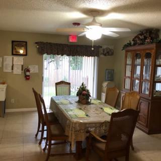 A cozy dining room featuring a table with chairs, a ceiling fan, and a china cabinet by the sliding door.