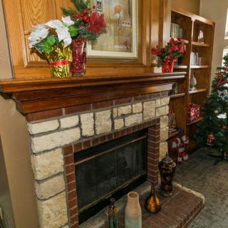 A cozy living room corner featuring a decorated fireplace mantel and a Christmas tree.