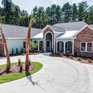 A suburban house with a circular driveway and landscaped yard.