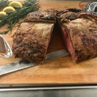A succulent roast beef sliced on a wooden cutting board, garnished with lemons and rosemary.