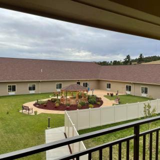 A view overlooking a courtyard garden with a surrounding building and overcast sky.