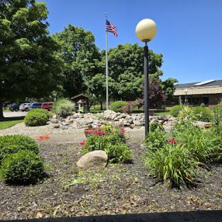 A serene garden scene featuring a flag and decorative landscaping under a clear blue sky.