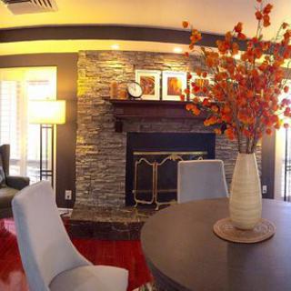 A cozy living room featuring a stone fireplace and modern decor accents, including a vase with vibrant flowers.