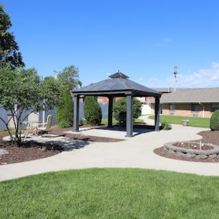 A serene park scene featuring a gazebo surrounded by lush greenery and a well-maintained walking path.