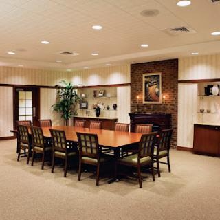A well-appointed conference room featuring a large wooden table surrounded by chairs, complemented by decorative wall art and indoor plants.