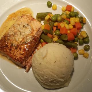 A dinner plate featuring salmon, mashed potatoes, and mixed vegetables.