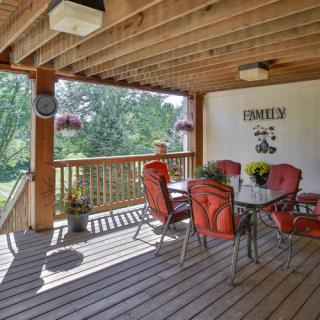 A cozy outdoor patio with a wooden deck and red cushioned chairs overlooking a garden.