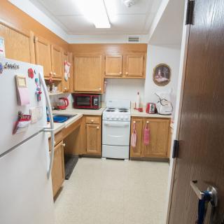 A small kitchen with wooden cabinets, a refrigerator, an oven, a microwave, and a sink.