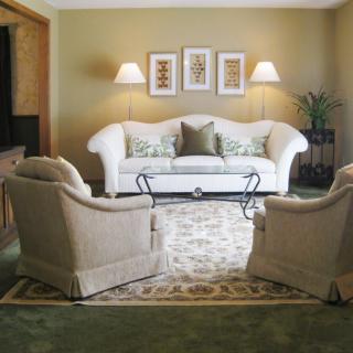 A cozy living room with a white sofa, patterned carpet, and matching armchairs.