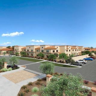 A view of a modern apartment complex with a parking lot on a sunny day.