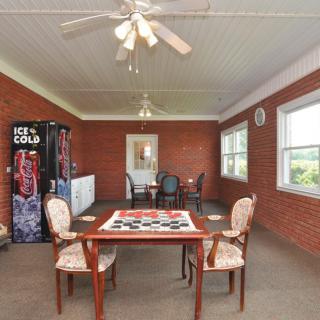 A dining area with a table, chairs, ceiling fan, and vending machine against brick walls.