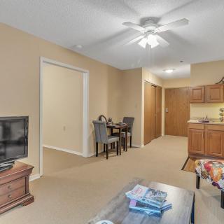A cozy living space featuring a TV, dining table, and kitchen area with warm lighting.