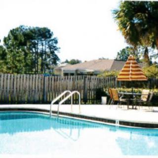 An inviting outdoor swimming pool with nearby patio furniture and an umbrella.