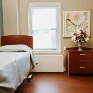 A simple bedroom with a single bed, nightstand, and floral decorations.