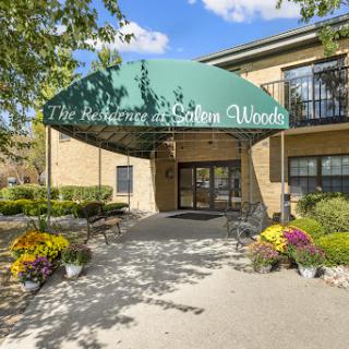 The entrance of a residential building adorned with colorful flowers and a green canopy.