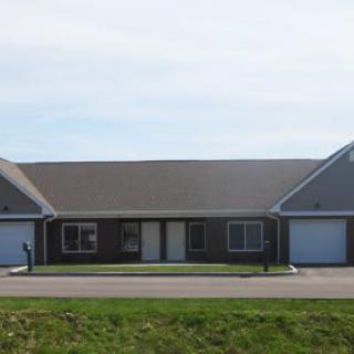 A suburban duplex featuring two garages and a small front yard.