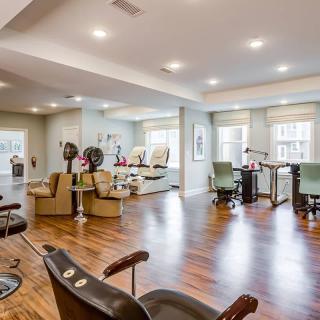 A spacious and well-lit beauty salon with multiple chairs and hair dryers.