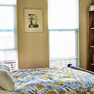 A cozy bedroom with a floral bedspread and natural light.