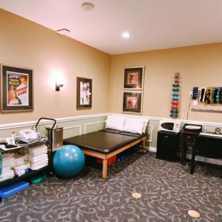 A well-equipped physical therapy room featuring exercise equipment and treatment tables.