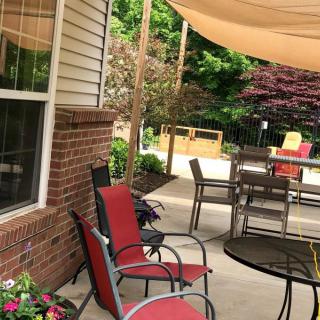A cozy outdoor patio with seating, tables, and a shade sail.