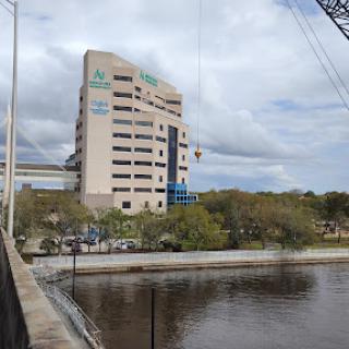 A view of a modern building situated by the river, under a cloudy sky.