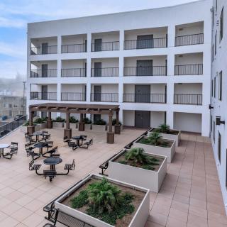 A modern building with an outdoor terrace featuring seating areas and planters.