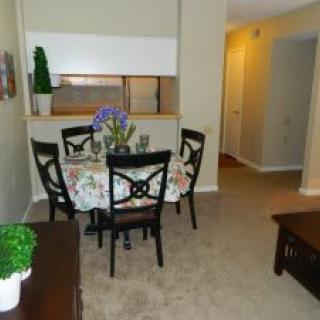A cozy dining area with a table set for four, featuring floral decorations and indoor plants.