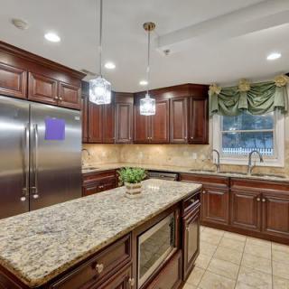 A modern kitchen featuring granite countertops, wood cabinetry, and stainless steel appliances.