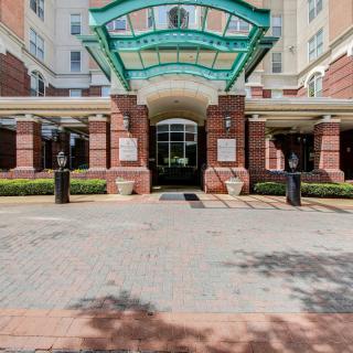 The main entrance of a modern building with a green canopy and brick facade.