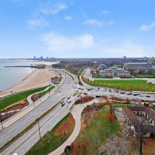 Aerial view of a city with a lakefront, roads, and a skyline in the background.
