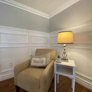 A cozy corner featuring an armchair and a side table with a lamp.