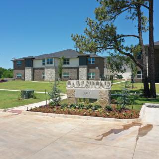 A residential housing complex with neatly maintained landscaping and a prominent entrance sign.