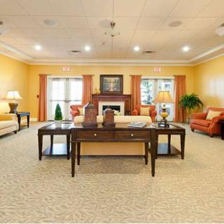A spacious living room with warm yellow walls, elegant furniture, and a cozy fireplace.