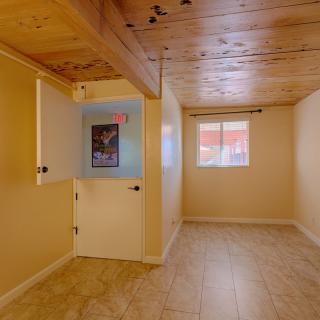 A cozy room with a wooden ceiling, tiled floor, and a window providing natural light.