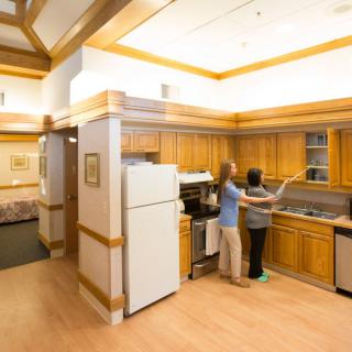 Two people preparing a meal in a modern kitchen with wood cabinets.