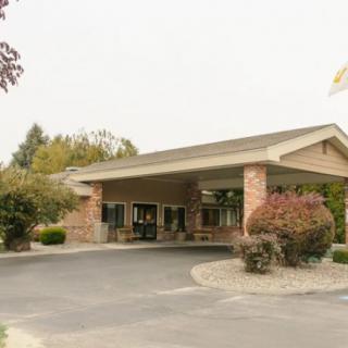 A view of a building entrance with a surrounding landscaped area and driveway.