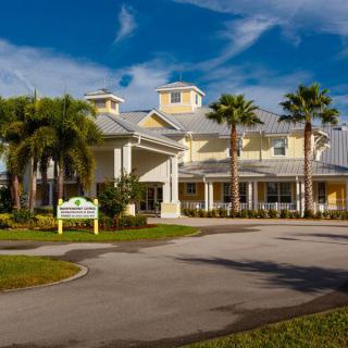 A sunny view of a tropical resort entrance with palm trees lining the driveway.