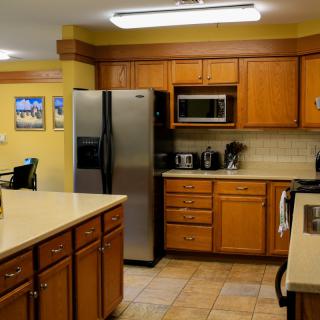 A modern kitchen with wooden cabinets, stainless steel appliances, and a tiled floor.