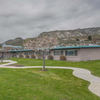 A view of a school building set against a mountainous landscape under a cloudy sky.