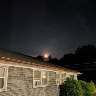 A serene night view featuring the moon rising behind a building.