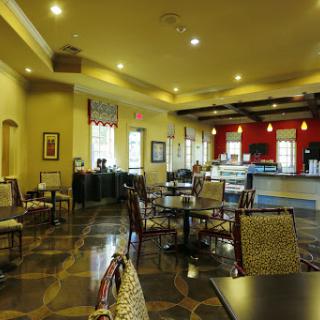 A cozy dining area in a restaurant, featuring elegant chairs and tables under warm lighting.