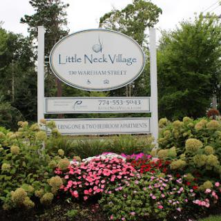 Welcome to Little Neck Village, surrounded by vibrant flowers and lush greenery.