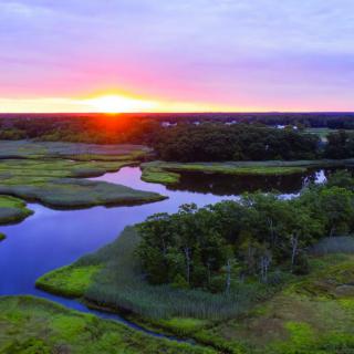 A picturesque view of a river winding through lush wetlands at sunset.