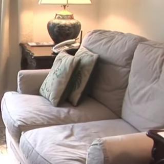 A cozy living room setup featuring a cushioned sofa with decorative pillows next to a side table and lamp.