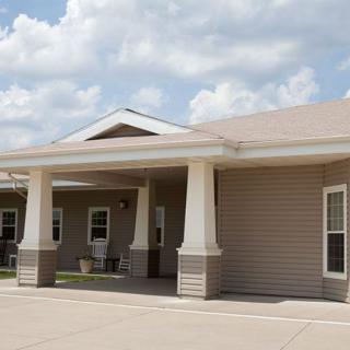 A residential building with a front porch under a cloudy sky.