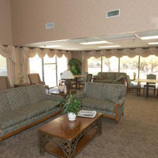 A spacious living room with sofas, a coffee table, and large windows with curtains.